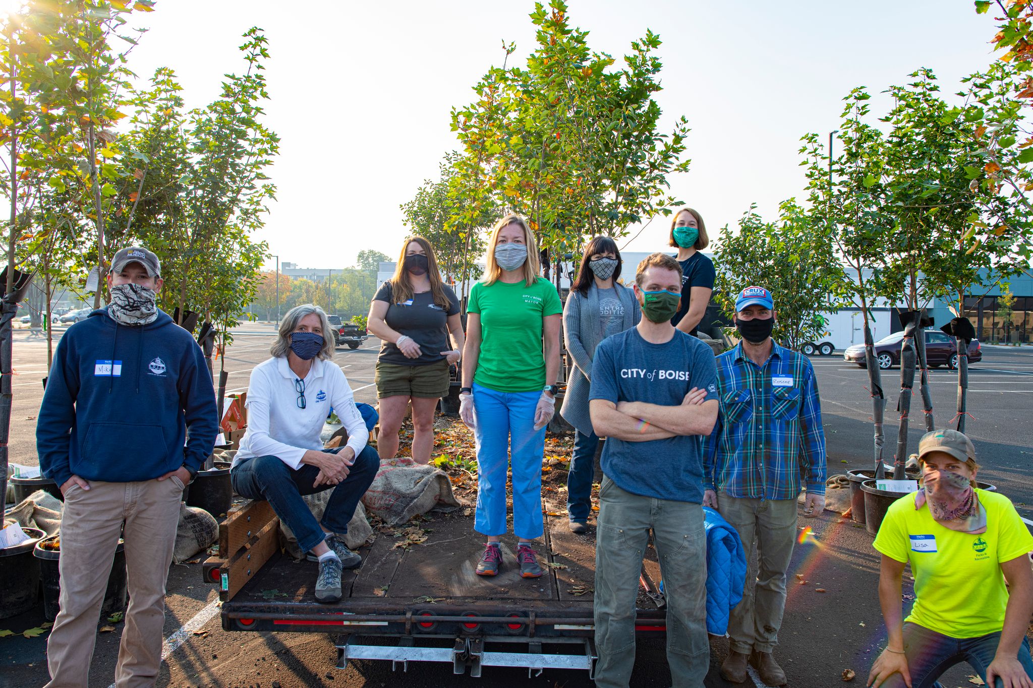 A group of people stand with potted trees.