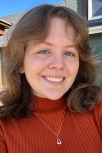 A young woman, smiling, wearing a red shirt.