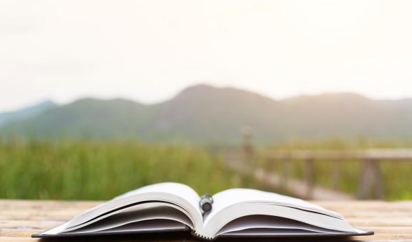 An open book set in front of a green field