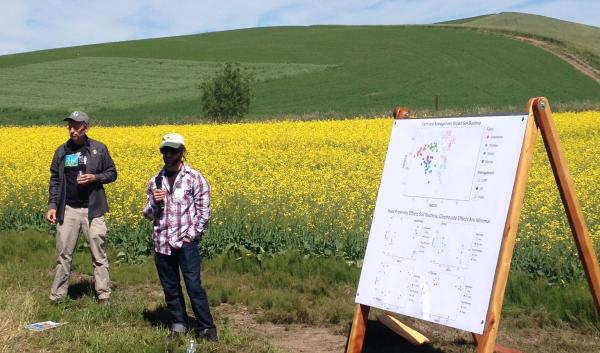 2 people standing in field with poster presenting data